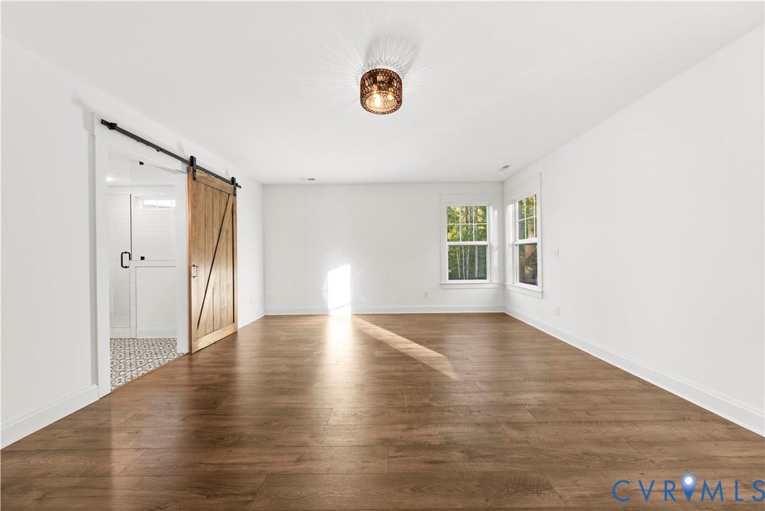 2613 Lilybank Place, NewMarket At RounTrey, Midlothian, VA 23112 Interior space featuring wood-finish flooring, a decorative metal drum light fixture, and a sliding wood-tone barn door with matte black hardware