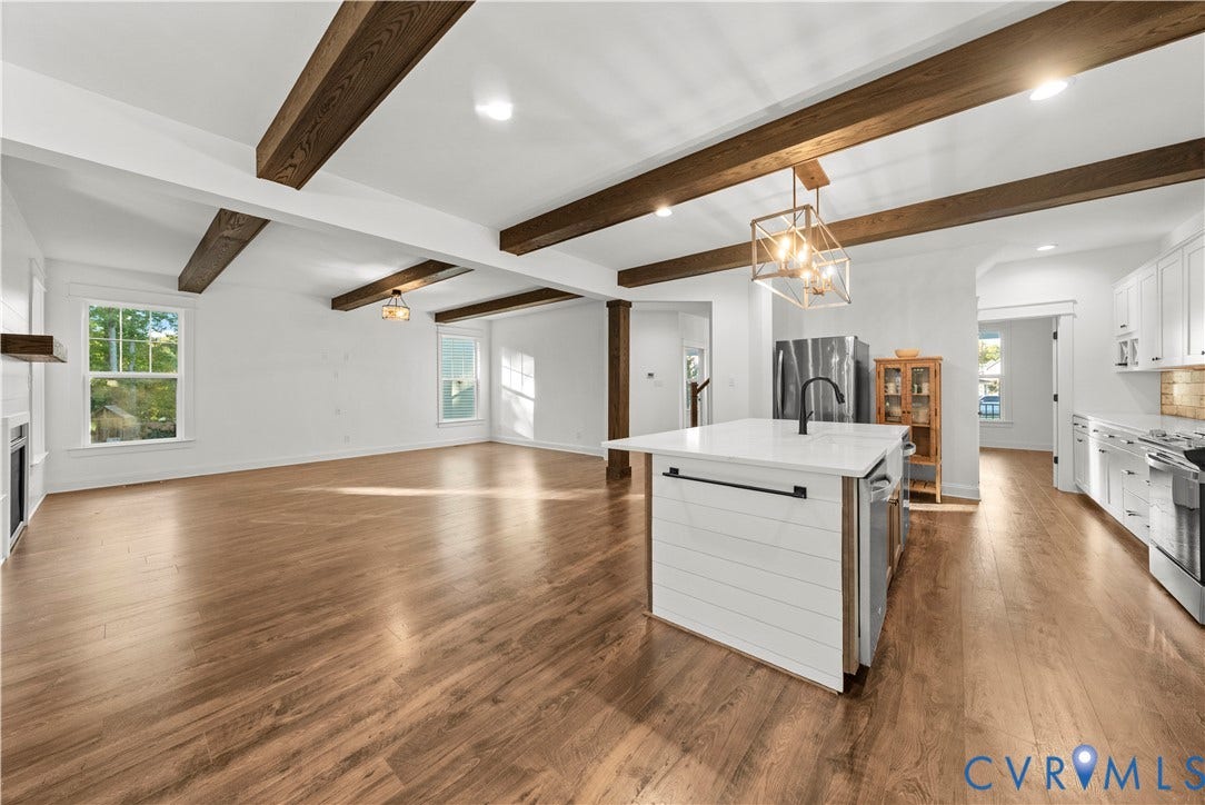 2613 Lilybank Place, NewMarket At RounTrey, Midlothian, VA 23112 Open-concept interior featuring exposed wood ceiling beams, white cabinetry, a center island with a shiplap facade and solid surface countertop, and wood-finish flooring