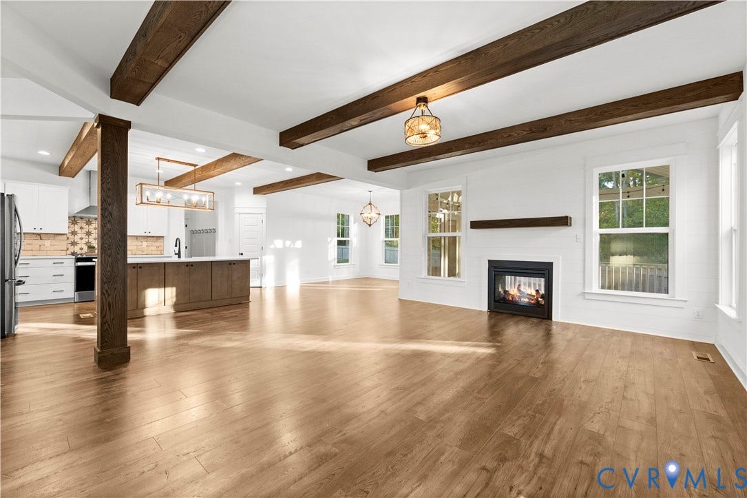 2613 Lilybank Place, NewMarket At RounTrey, Midlothian, VA 23112 Open-concept space featuring exposed dark wood ceiling beams, wood-finish flooring, a fireplace with a wood mantel, and kitchen cabinetry with a central island