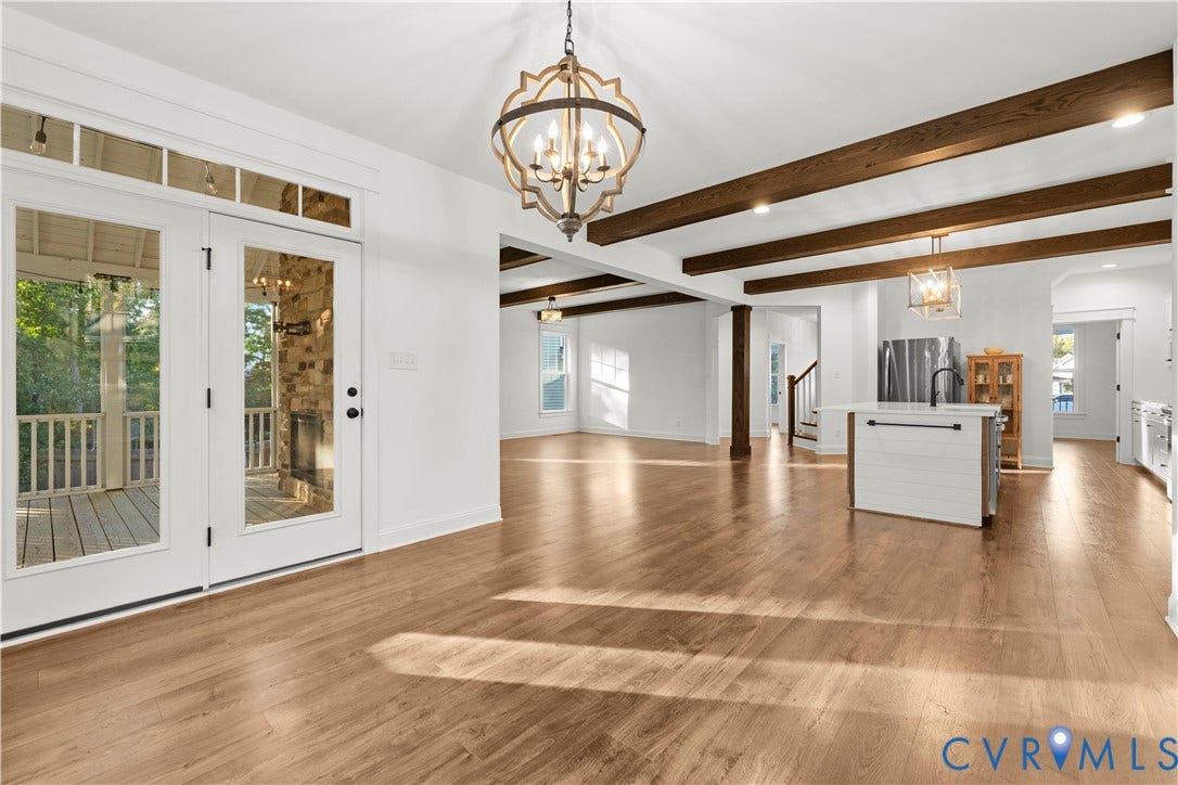 2613 Lilybank Place, NewMarket At RounTrey, Midlothian, VA 23112 Open-concept interior featuring wood-finish flooring, exposed stained-wood ceiling beams, a decorative iron chandelier, a center kitchen island, and glass-paneled double doors with transom windows