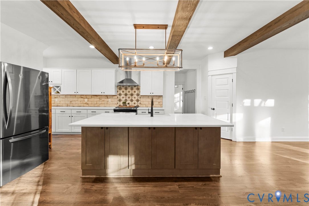 2613 Lilybank Place, NewMarket At RounTrey, Midlothian, VA 23112 Kitchen featuring white shaker-style cabinetry, center island with stone-surface countertop, exposed stained-wood ceiling beams, patterned tile backsplash, and wood-finish flooring