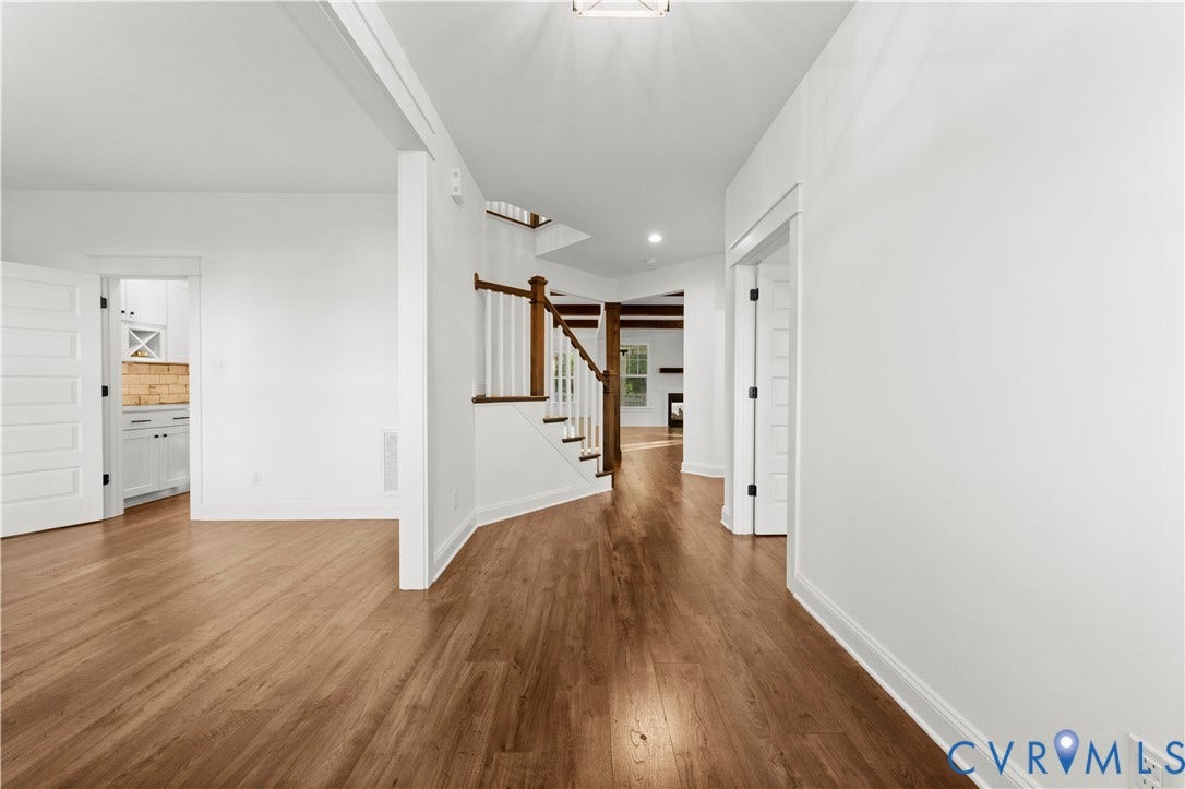 2613 Lilybank Place, NewMarket At RounTrey, Midlothian, VA 23112 Interior entry featuring wood-finish flooring, a staircase with a wooden handrail and white balusters, and multi-panel doors with matte black hardware