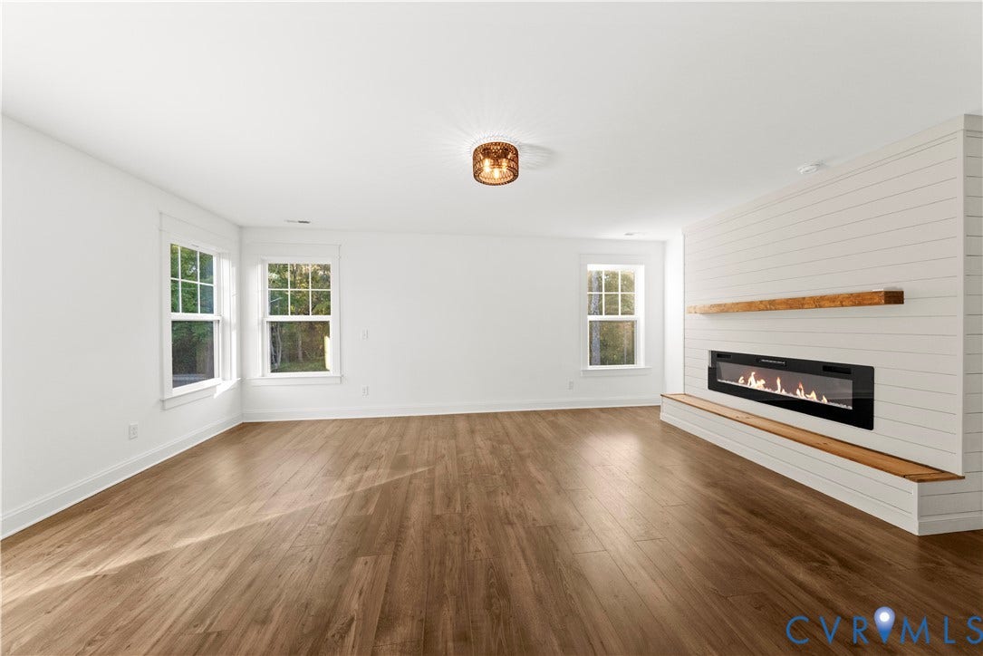 2613 Lilybank Place, NewMarket At RounTrey, Midlothian, VA 23112 Wood-finish flooring, white shiplap accent wall, built-in linear fireplace, natural wood mantel and hearth, and multi-pane windows