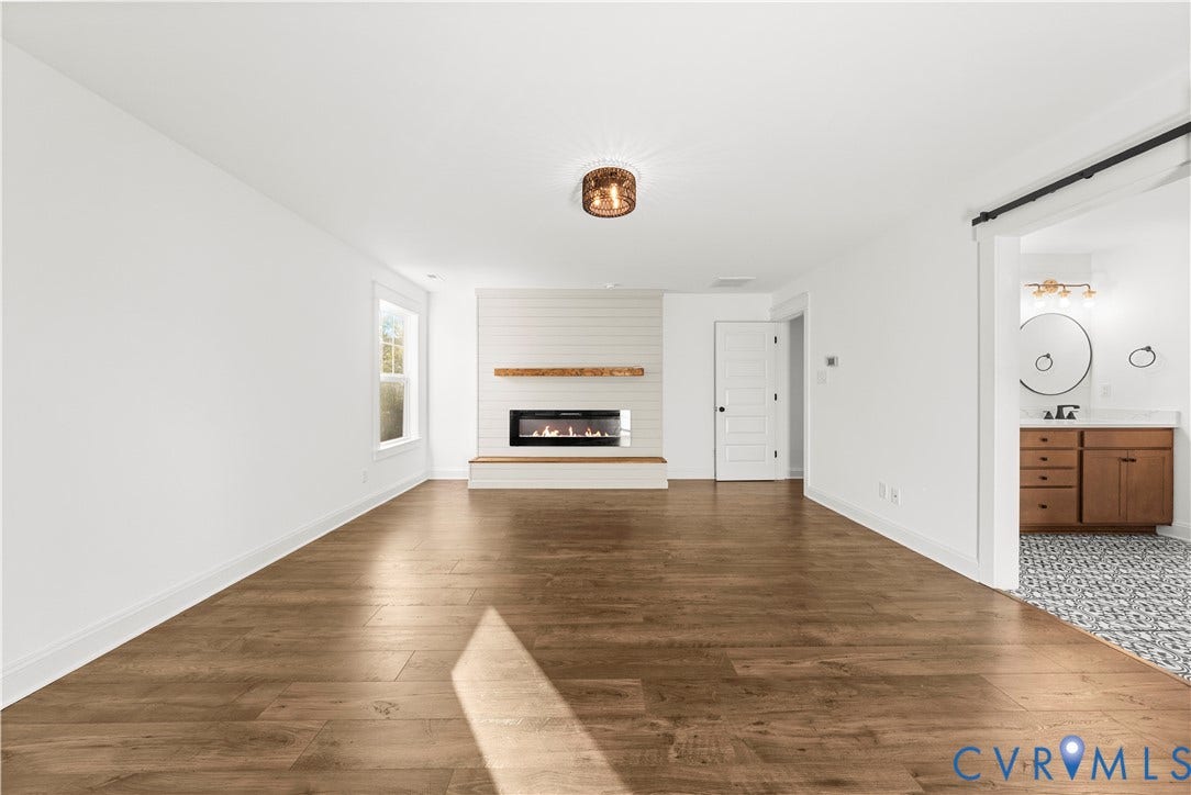 2613 Lilybank Place, NewMarket At RounTrey, Midlothian, VA 23112 Wood-finish flooring, horizontal shiplap accent wall, built-in linear fireplace with natural wood mantel, and custom farmhouse-style door hardware