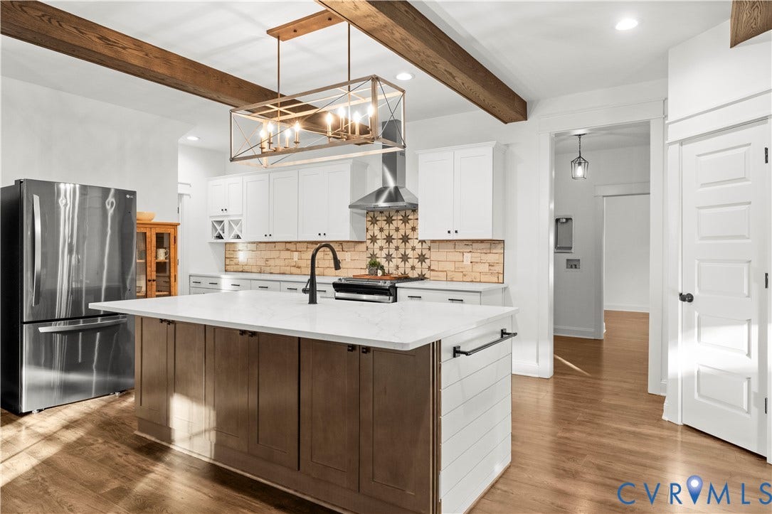 2613 Lilybank Place, NewMarket At RounTrey, Midlothian, VA 23112 Kitchen featuring a central island with a solid surface countertop, white shaker-style cabinetry, a patterned tile backsplash, wood-finish flooring, and exposed ceiling beams