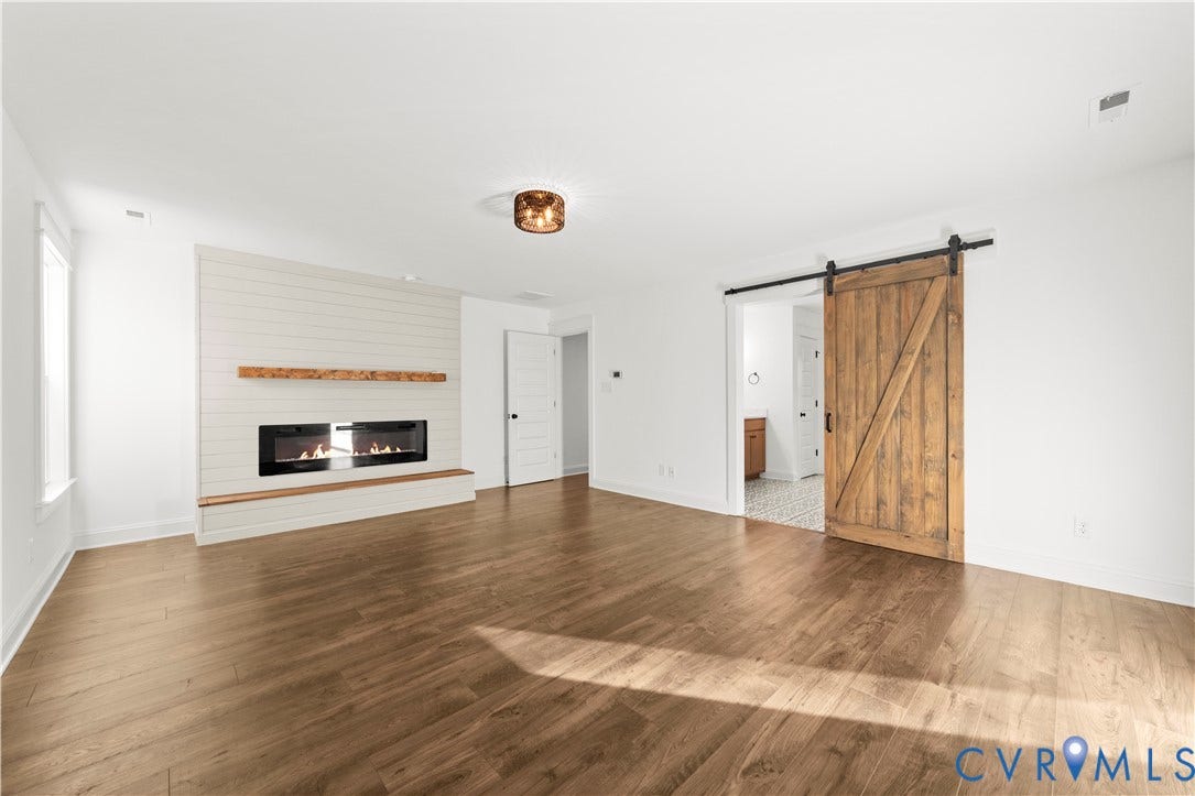 2613 Lilybank Place, NewMarket At RounTrey, Midlothian, VA 23112 Wood-finish flooring, horizontal shiplap fireplace surround, built-in wooden mantel, inset linear electric fireplace, and sliding wooden barn door
