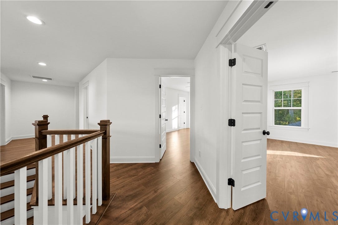 2613 Lilybank Place, NewMarket At RounTrey, Midlothian, VA 23112 Interior landing featuring wood-finish flooring, recessed lighting, white five-panel doors, and a wood-capped staircase with white balusters