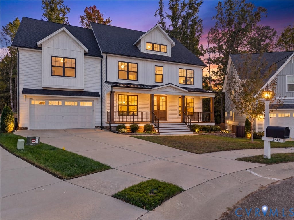 2613 Lilybank Place, NewMarket At RounTrey, Midlothian, VA 23112 Two-story residence featuring a white vertical-board exterior, a covered front porch with metal railing, a shingled roof with a front-facing gable, and an attached two-car garage