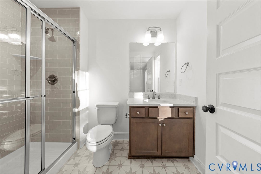2613 Lilybank Place, NewMarket At RounTrey, Midlothian, VA 23112 Bathroom featuring a glass-enclosed shower with subway tile surround, vanity with stone-finish countertop, patterned tile flooring, and integrated wall-mounted lighting
