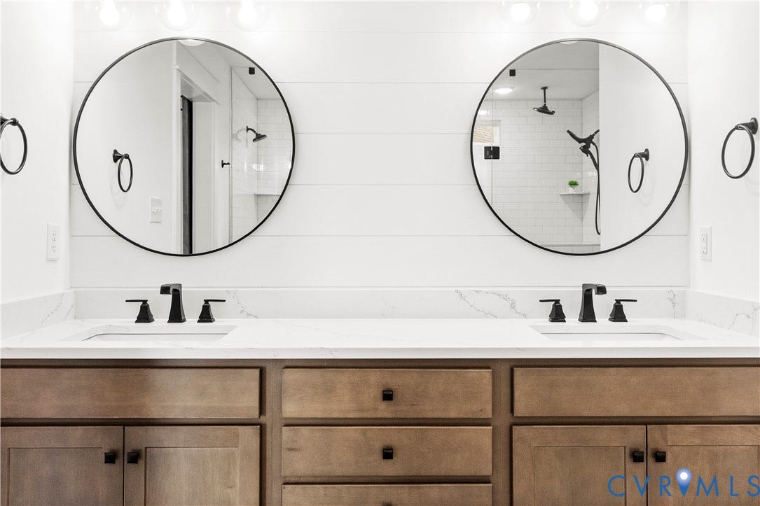 2613 Lilybank Place, NewMarket At RounTrey, Midlothian, VA 23112 Double vanity featuring wood-finish cabinetry, white stone-composite countertops, dual circular mirrors with black frames, and matte black plumbing fixtures set against shiplap wall detailing