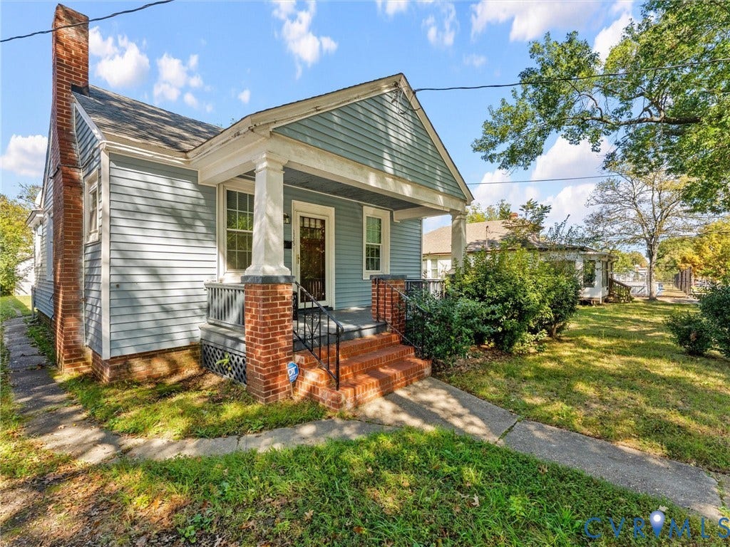 2305 Halifax Avenue, Oak Grove, Sandston, VA 23224 Blue siding exterior featuring a prominent brick chimney, a covered front porch with square columns, brick porch supports, and stairs