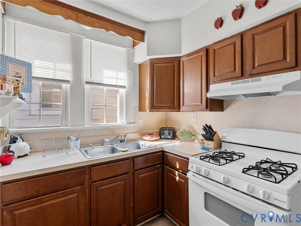 2305 Halifax Avenue, Oak Grove, Sandston, VA 23224 Kitchen featuring wood cabinetry, solid-surface countertops, a double-basin stainless steel sink, and large windows with blinds