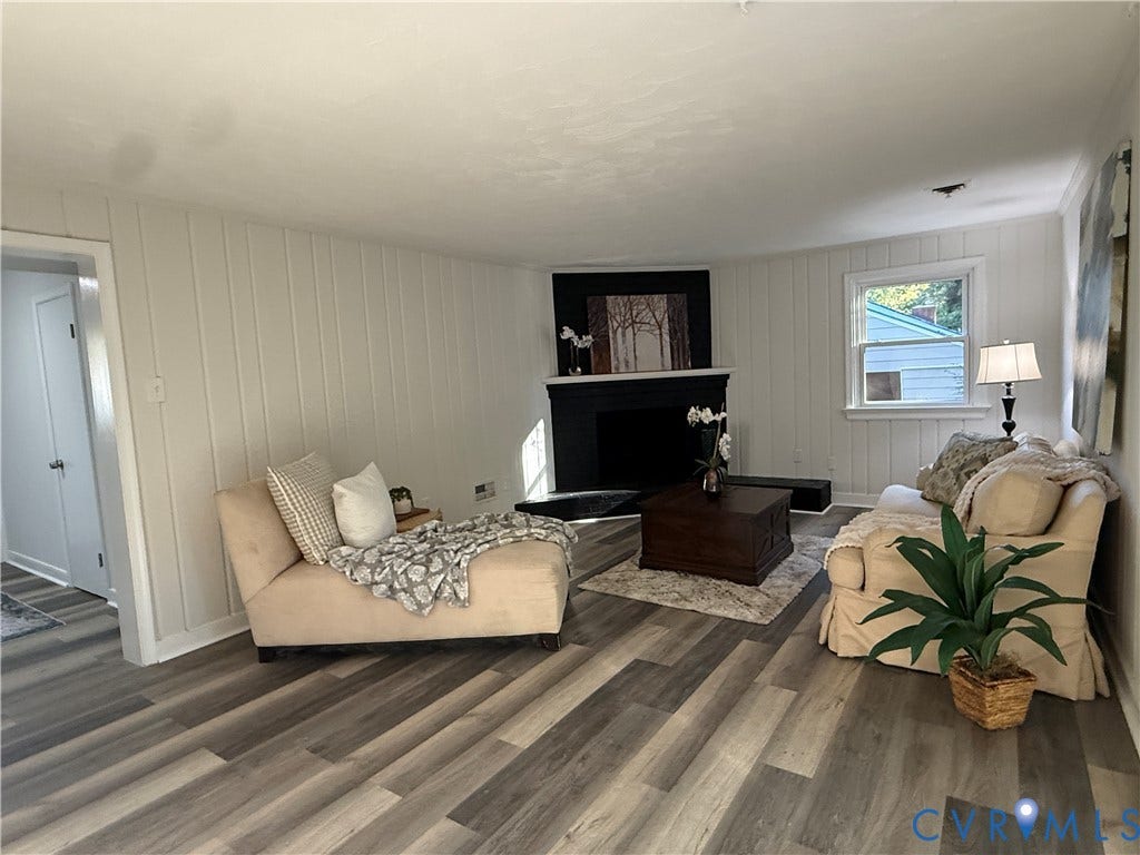 533 Williamsdale Drive, Midlothian, VA 23235 Living area featuring vertical paneled walls, wood-finish flooring, and a corner fireplace with a black surround and mantle
