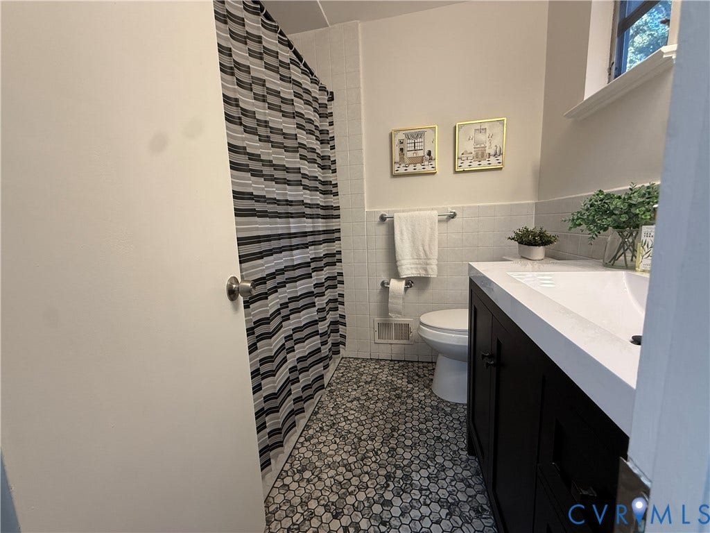 533 Williamsdale Drive, Midlothian, VA 23235 Bathroom featuring a dark-finish vanity with a rectangular sink, white countertop, hexagon tile flooring, and wall-tiled tub enclosure