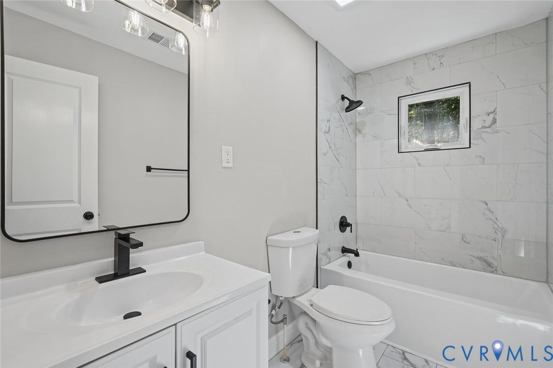 15227 Horseshoe Bridge Road, Hanover, VA 23047 Bathroom featuring white vanity cabinetry, rectangular mirror with black frame, matte black hardware, and tub surround finished with white tile