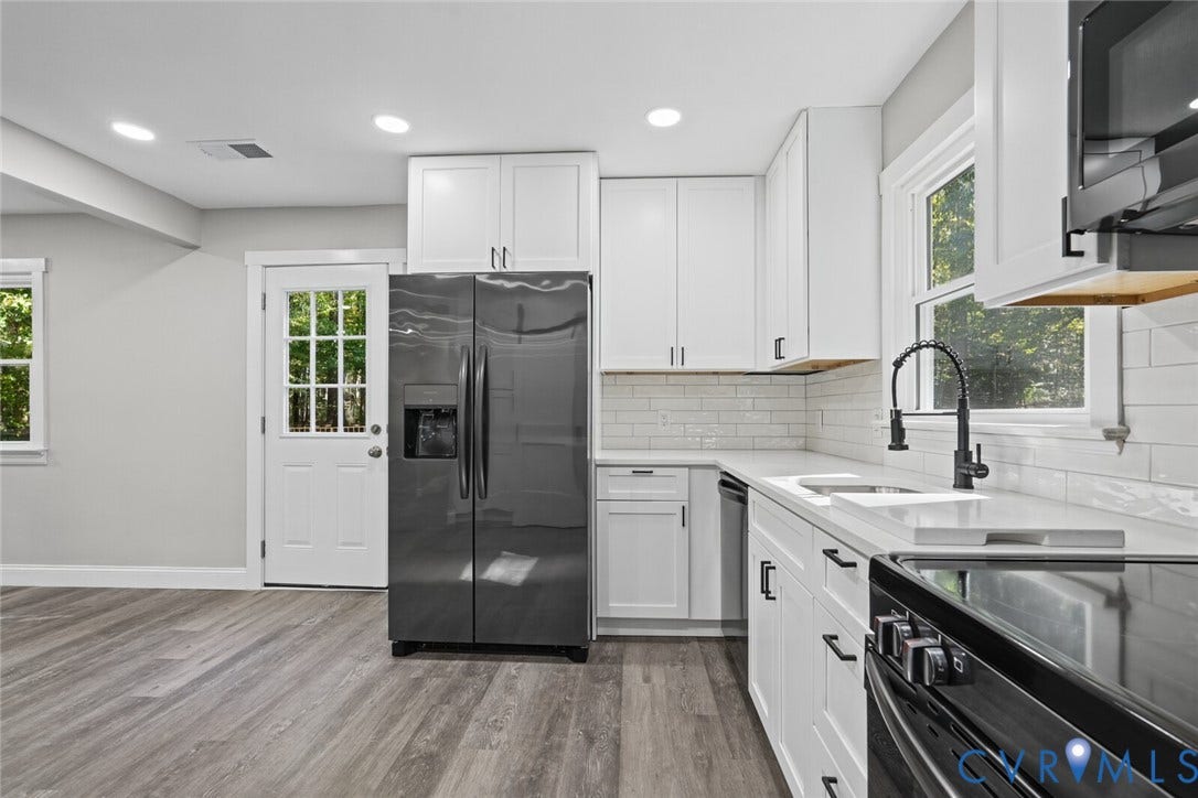 15227 Horseshoe Bridge Road, Hanover, VA 23047 Kitchen featuring white shaker-style cabinetry, light-toned stone countertops, a subway tile backsplash, dark-finish hardware, and wood-finish flooring