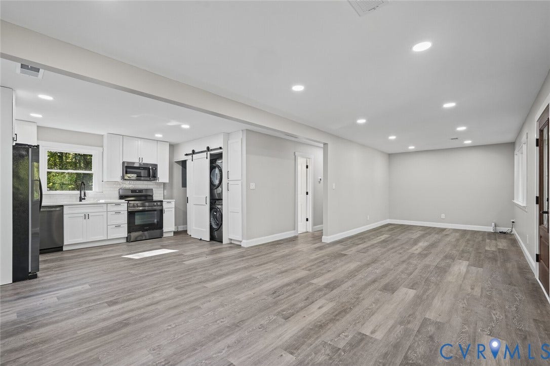 15227 Horseshoe Bridge Road, Hanover, VA 23047 Kitchen area featuring white shaker-style cabinetry, stainless steel appliances, wood-finish flooring, recessed lighting, and a sliding barn door concealing a laundry station