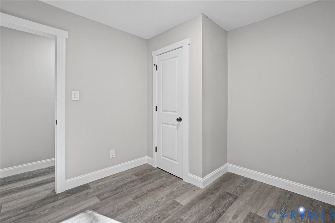 15227 Horseshoe Bridge Road, Hanover, VA 23047 Neutral interior space featuring wood-finish flooring, crisp white casing, and a two-panel interior door with matte black hardware