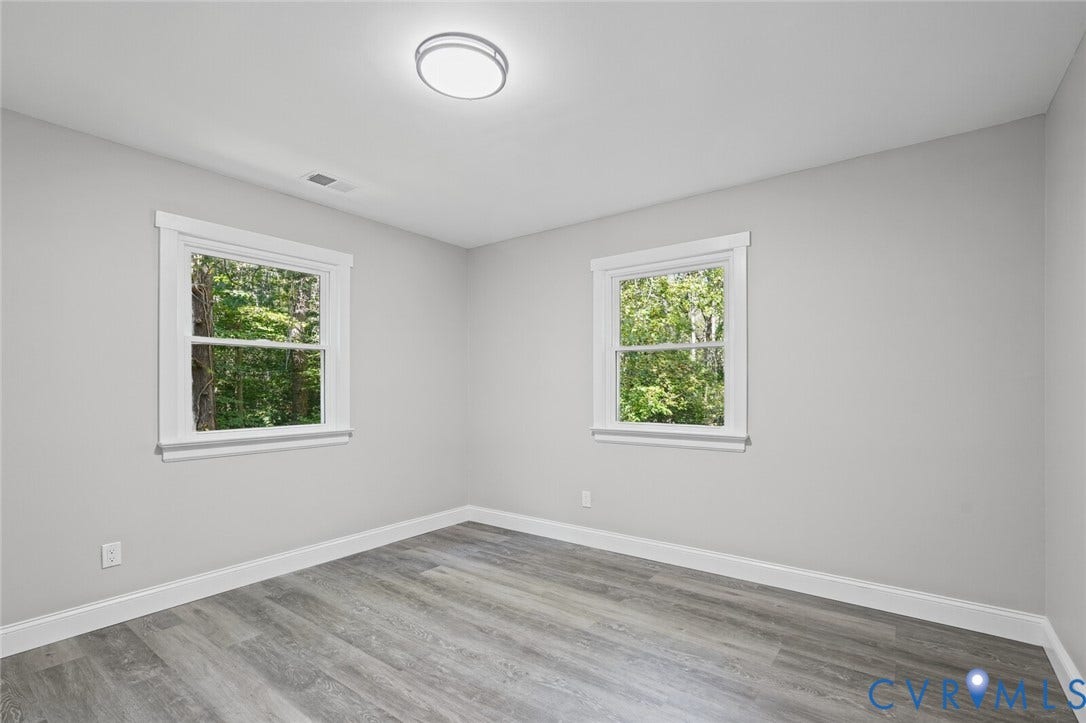 15227 Horseshoe Bridge Road, Hanover, VA 23047 Neutral interior featuring wood-finish flooring, two double-hung windows with white casing, and a flush-mount overhead light fixture