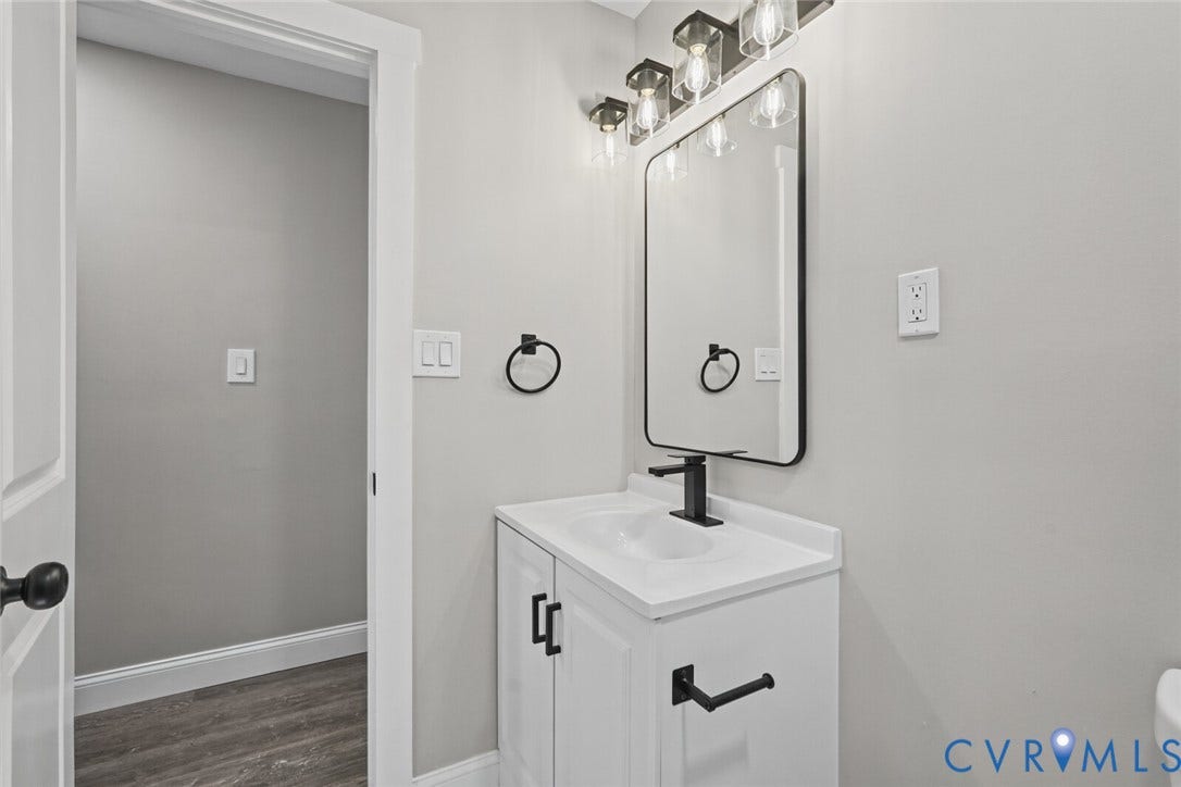 15227 Horseshoe Bridge Road, Hanover, VA 23047 White vanity cabinet with an integrated sink, rectangular mirror with a black frame, matte black faucet, and coordinating black hardware
