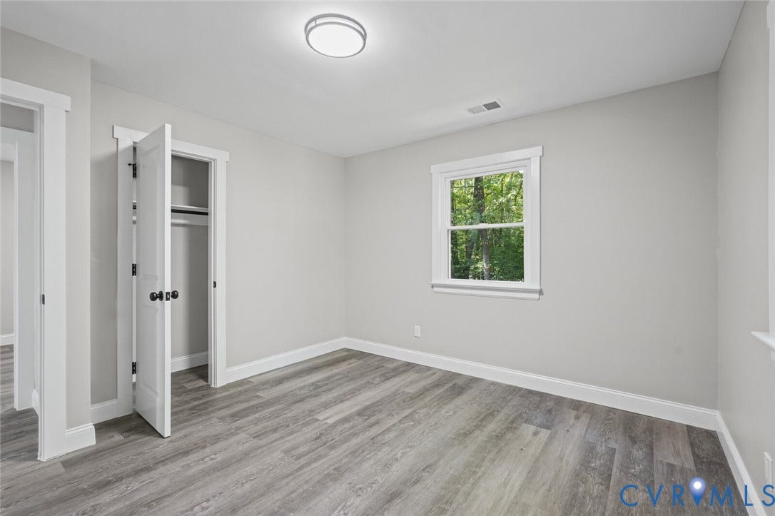 15227 Horseshoe Bridge Road, Hanover, VA 23047 Neutral interior room featuring wood-finish flooring, crisp white trim, a single-hung window, and a built-in closet with a panel door