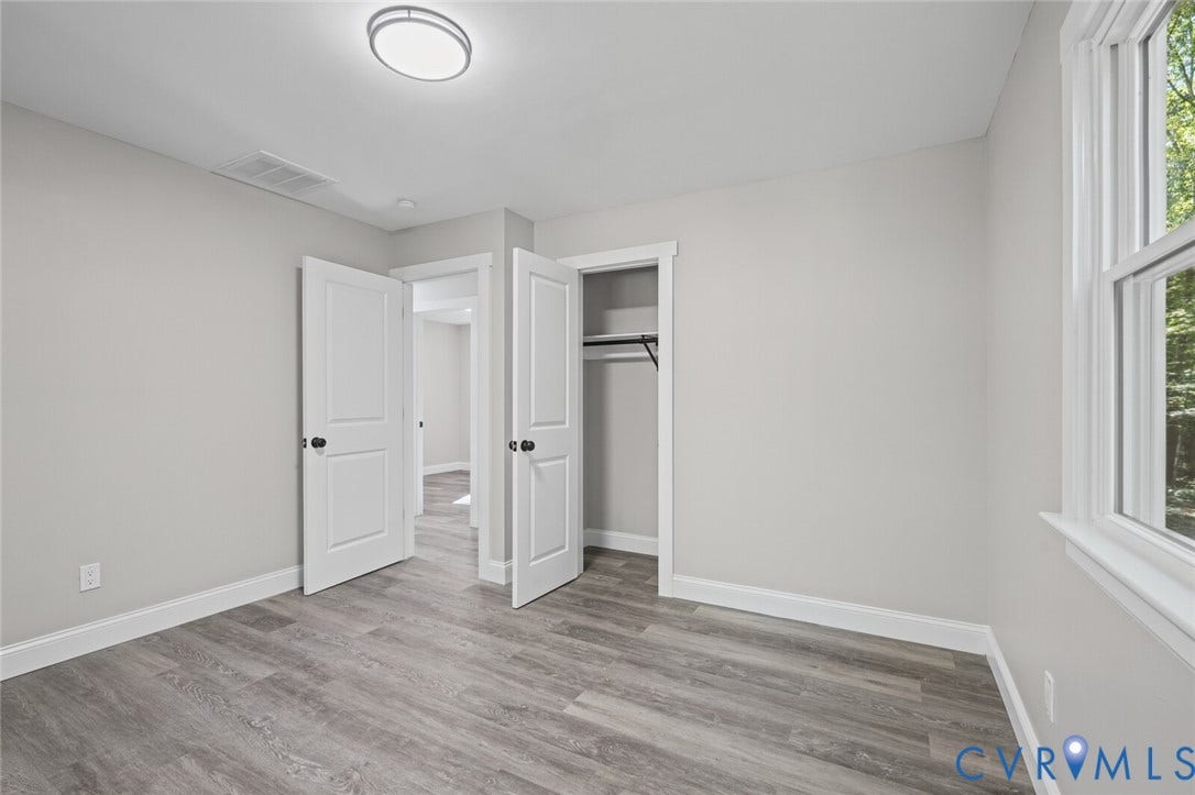 15227 Horseshoe Bridge Road, Hanover, VA 23047 Neutral-toned interior featuring wood-finish flooring, two-panel interior doors with matte black hardware, and an integrated closet with shelving