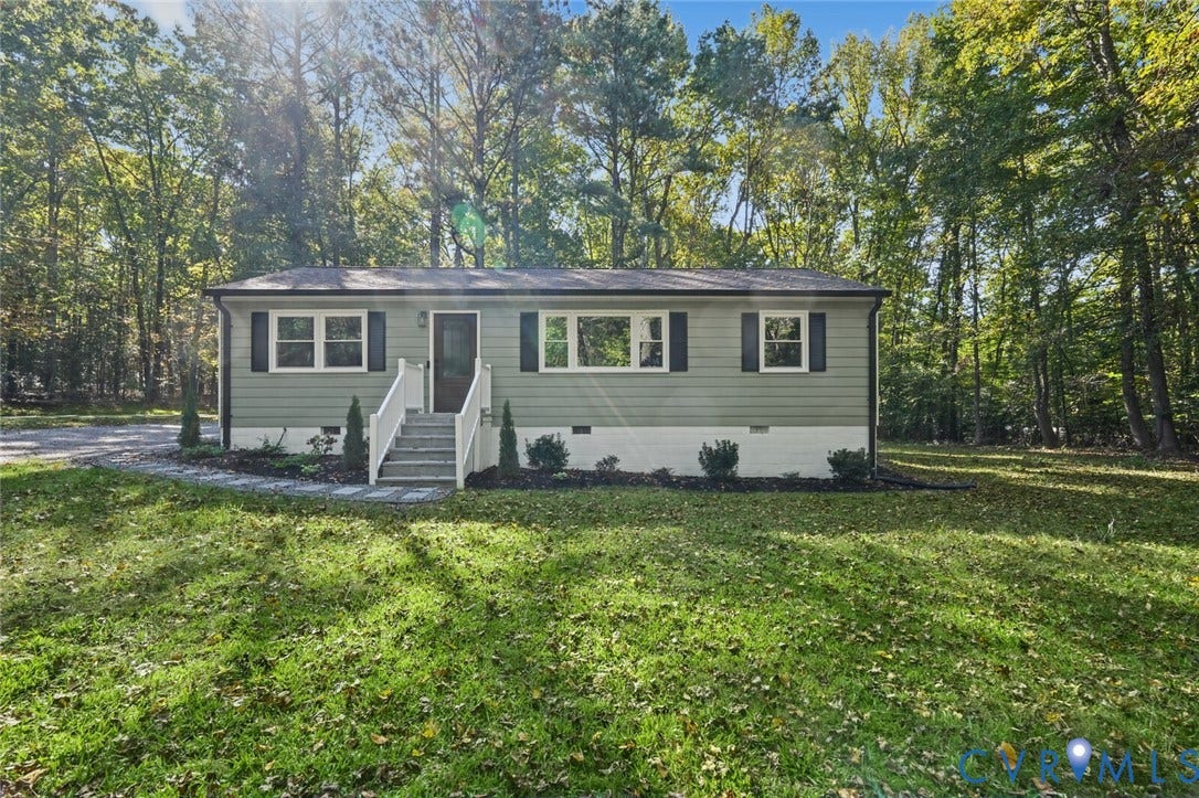 15227 Horseshoe Bridge Road, Hanover, VA 23047 Single-story exterior featuring light-toned horizontal siding, decorative window shutters, a stone paver walkway, white railings, and mature wooded surroundings