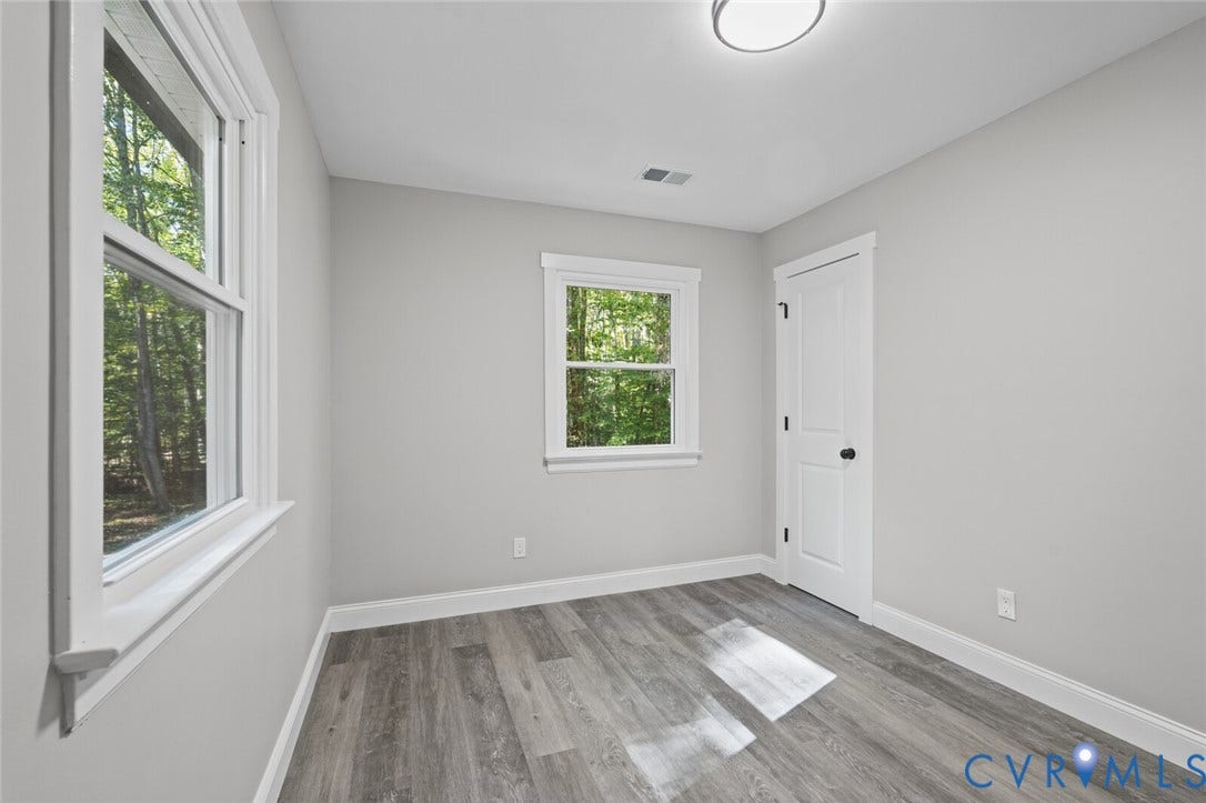 15227 Horseshoe Bridge Road, Hanover, VA 23047 Neutral-toned interior featuring wood-finish flooring, two double-hung windows with white trim, and a paneled interior door with matte black hardware