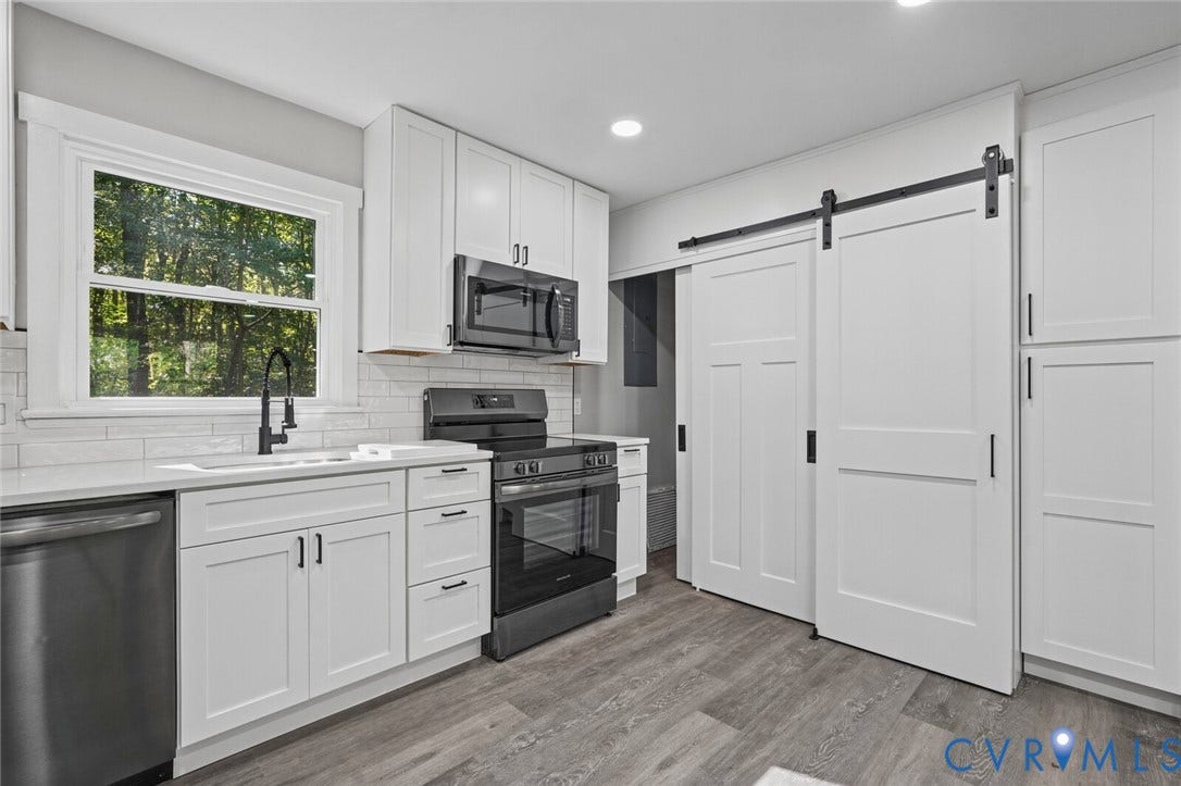 15227 Horseshoe Bridge Road, Hanover, VA 23047 Kitchen featuring white shaker-style cabinetry, quartz countertops, subway tile backsplash, stainless steel appliances, and a sliding barn door