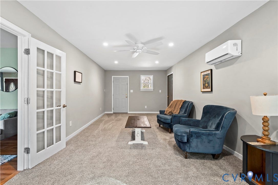 7040 Old Roxbury Road, Average, New Kent, VA 23141 Neutral-toned interior space featuring a ceiling fan, wall-mounted split-system air conditioning unit, and a white French door with glass panes