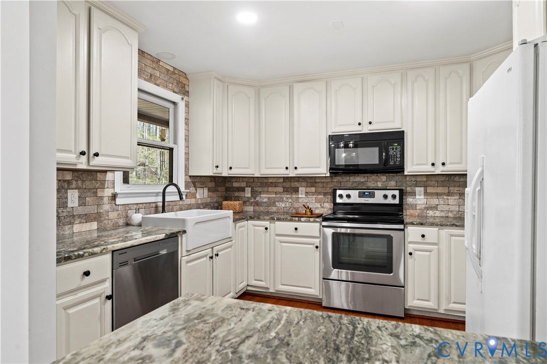 7040 Old Roxbury Road, Average, New Kent, VA 23141 Kitchen featuring cream-colored cabinetry, stone-style tile backsplash, farmhouse-style sink with a gooseneck faucet, stone countertops, and stainless steel appliances
