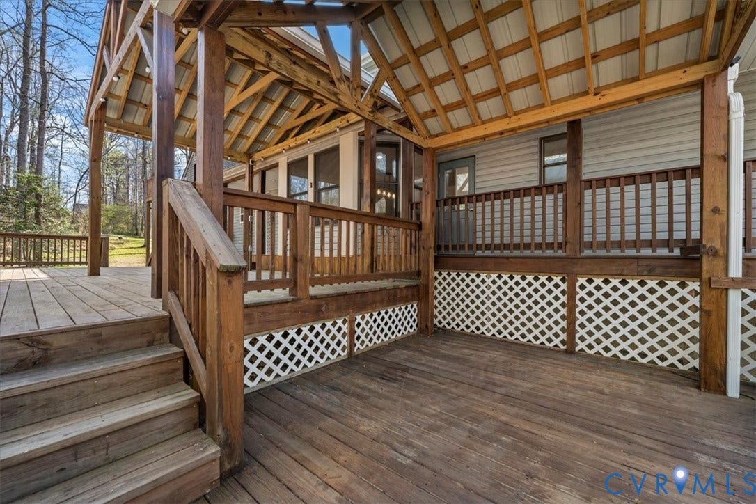 7040 Old Roxbury Road, Average, New Kent, VA 23141 Multi-level wooden deck featuring a covered gable roof, exposed timber framing, wooden railings, and white lattice skirting