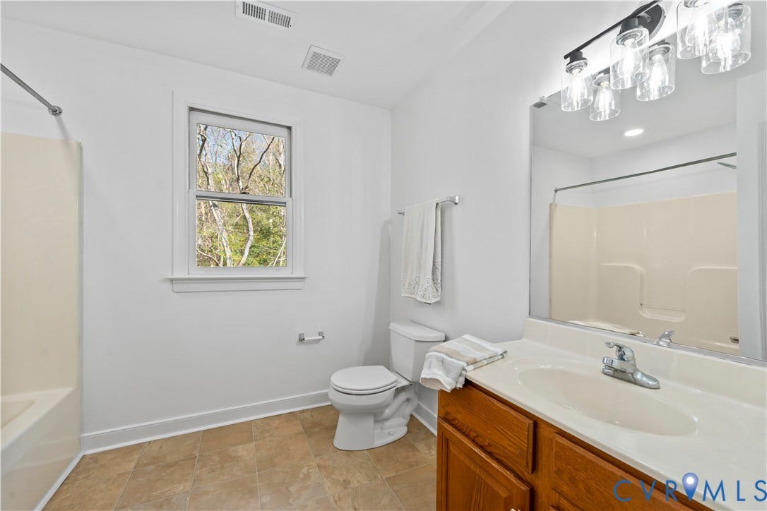 7040 Old Roxbury Road, Average, New Kent, VA 23141 Full bathroom featuring a wood-finish vanity with an integrated basin, a large-format mirror, multi-light fixture, and tile flooring