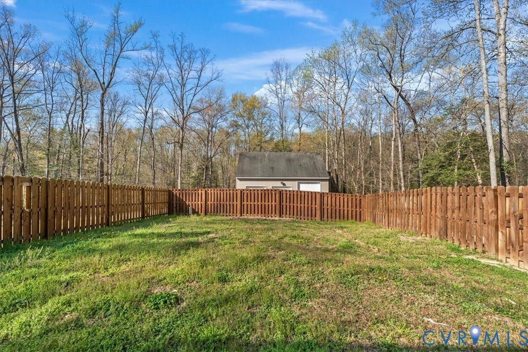 7040 Old Roxbury Road, Average, New Kent, VA 23141 Fenced backyard featuring wood-panel fencing, grass lawn, and mature trees
