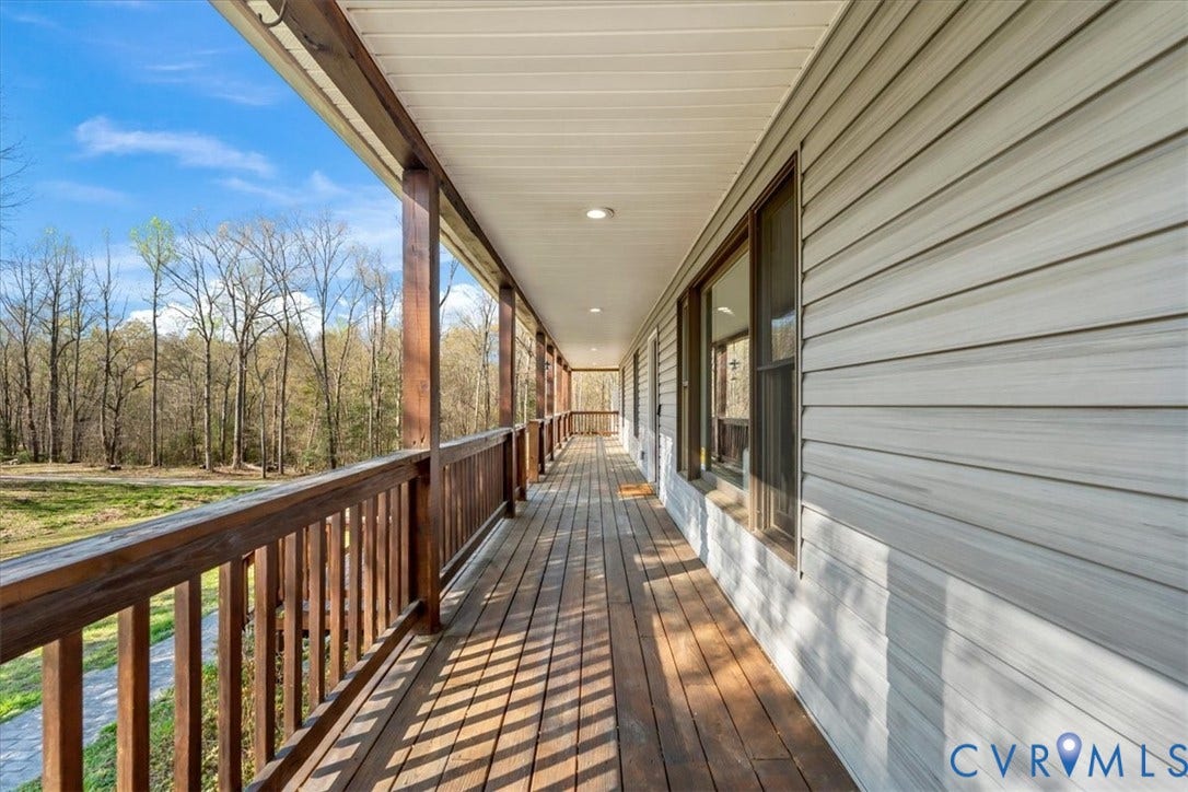7040 Old Roxbury Road, Average, New Kent, VA 23141 Covered wrap-around porch featuring wood-finish decking, stained wood railings, light-grey horizontal siding, and recessed ceiling lighting
