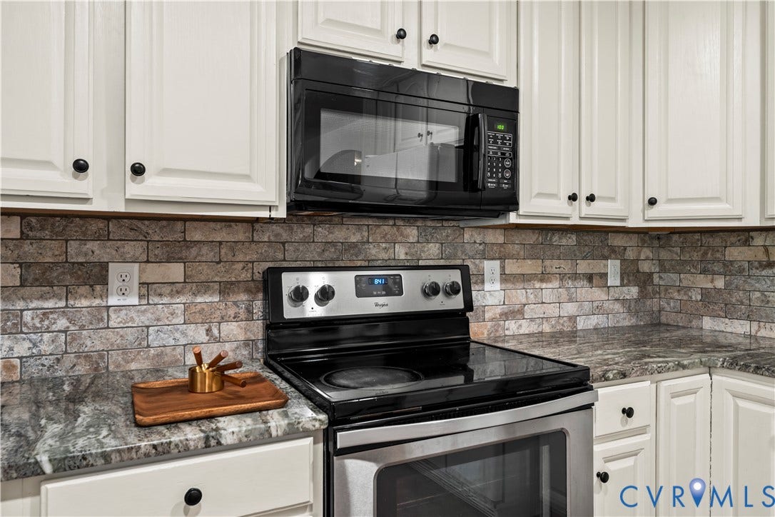 7040 Old Roxbury Road, Average, New Kent, VA 23141 Kitchen featuring shaker-style cabinetry, stone-finish countertops, brick-style tile backsplash, and integrated black-finish appliances