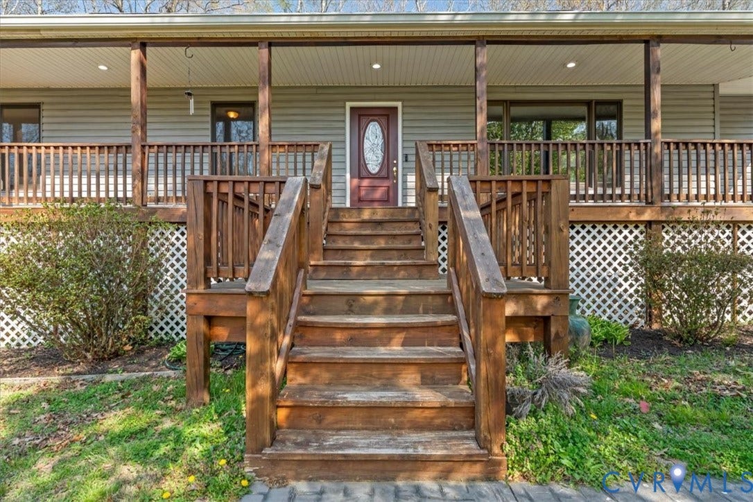 7040 Old Roxbury Road, Average, New Kent, VA 23141 Covered front porch featuring a wooden staircase, horizontal siding, lattice skirting, and a door with an oval glass inset