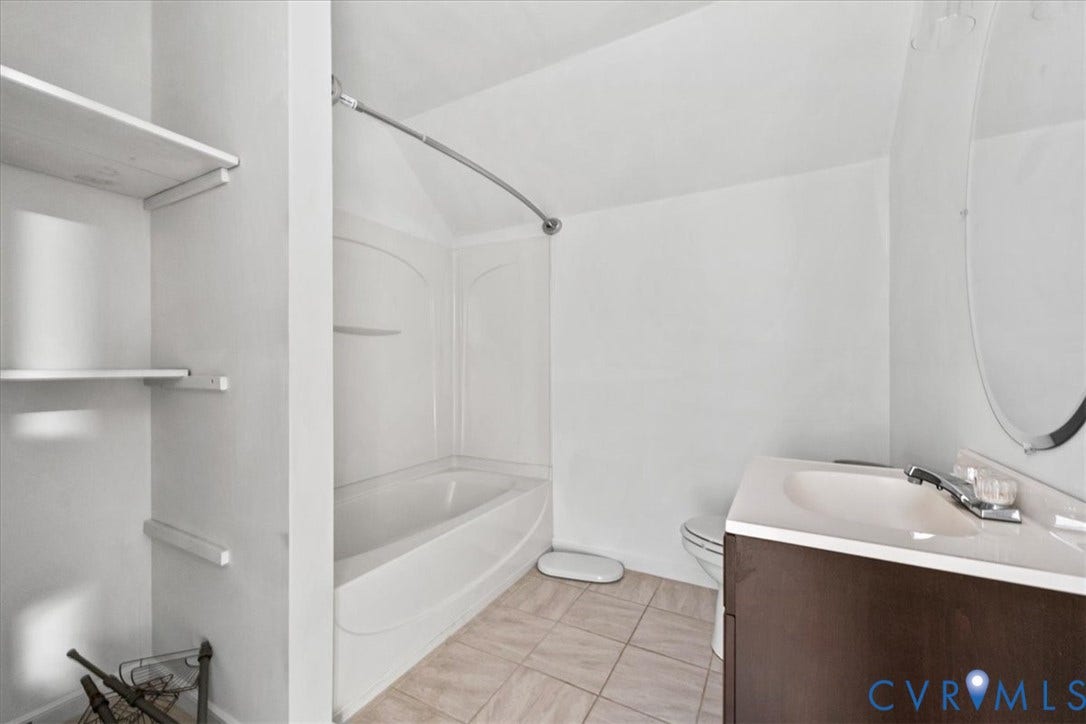 7040 Old Roxbury Road, Average, New Kent, VA 23141 Bathroom featuring a dark wood-finish vanity with a light-toned countertop, integrated tub and shower combination with a curved rod, oval wall mirror, and tile flooring
