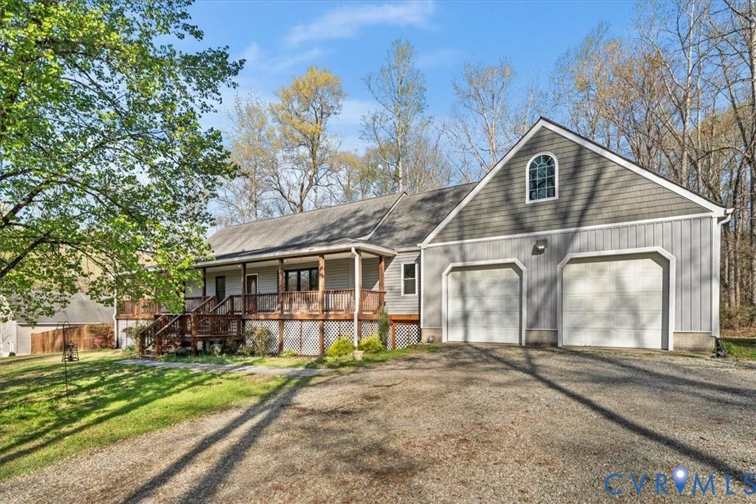 7040 Old Roxbury Road, Average, New Kent, VA 23141 Exterior featuring vertical and shingle siding, a covered wraparound wood porch, an attached two-car garage, and a semicircular arch window