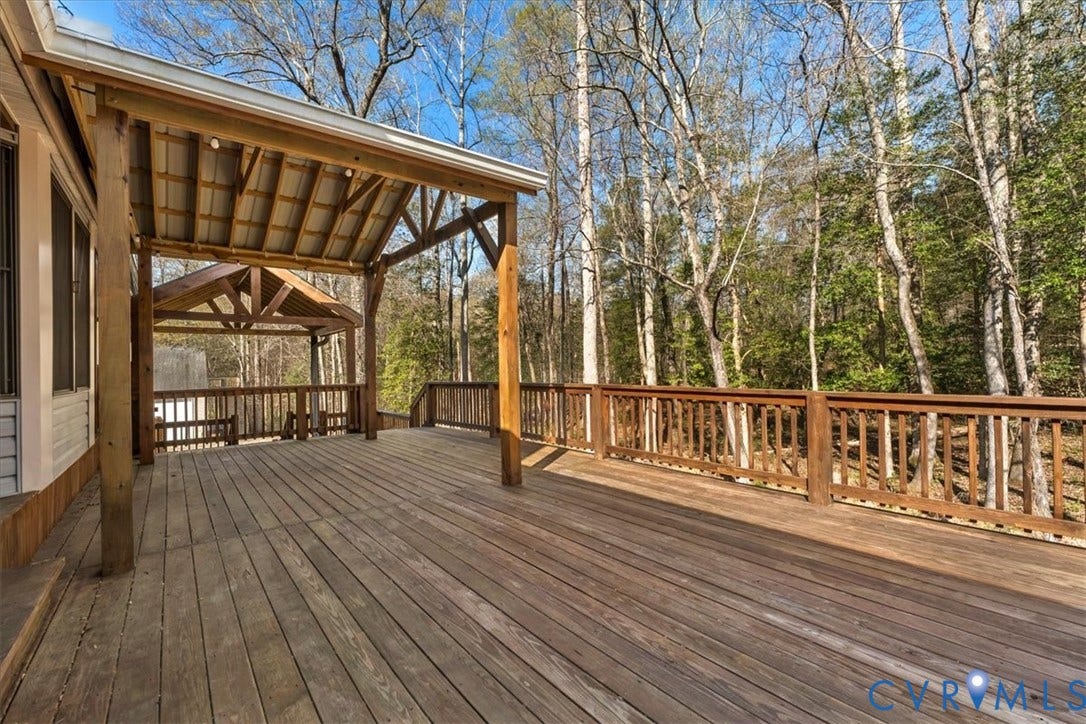 7040 Old Roxbury Road, Average, New Kent, VA 23141 Expansive wood deck featuring a covered timber-framed porch, exposed rafters, and wooden balustrades