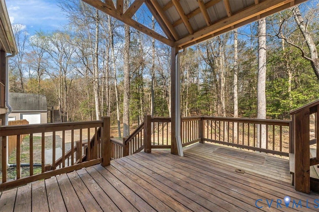 7040 Old Roxbury Road, Average, New Kent, VA 23141 Covered wooden deck featuring an exposed truss ceiling, perimeter wood railings, and stairs leading to the ground level
