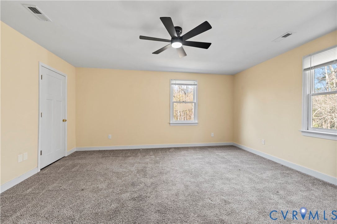7040 Old Roxbury Road, Average, New Kent, VA 23141 Neutral-toned walls, grey carpeting, multi-pane windows, and a matte black six-blade ceiling fan with integrated lighting