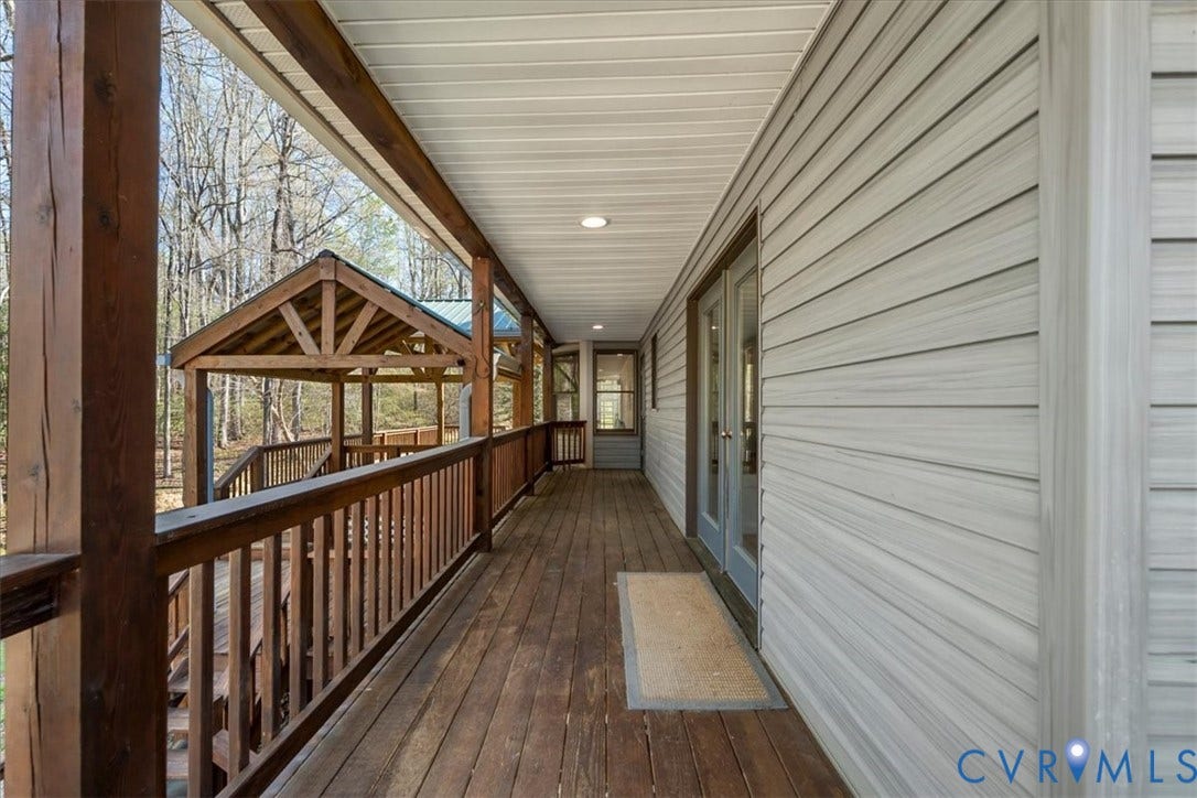 7040 Old Roxbury Road, Average, New Kent, VA 23141 Covered exterior deck featuring wood-finish flooring, dark timber support posts, horizontal siding, and a wooden gazebo structure