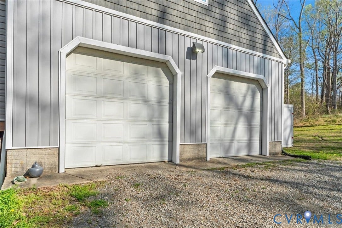 7040 Old Roxbury Road, Average, New Kent, VA 23141 Two-car garage featuring vertical siding, shake-shingle gable, concrete foundation, and dual overhead doors