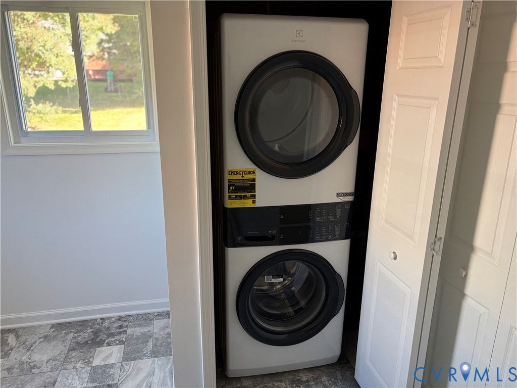 1708 Shewalt Drive, Fairfield, VA 23228 Stacked front-load laundry unit with digital controls, housed within a closet featuring white panel doors and set against stone-finish tile flooring