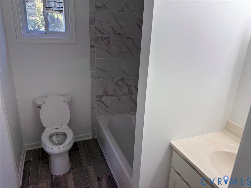 1708 Shewalt Drive, Fairfield, VA 23228 Bathroom 3rd level featuring a tub with stone-patterned tile surround, wood-finish flooring, a vanity with a solid-surface countertop, and a window