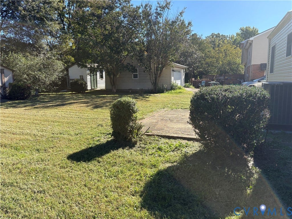 1708 Shewalt Drive, Fairfield, VA 23228 Expansive backyard featuring a grass lawn, mature trees, a concrete pad, and a detached garage