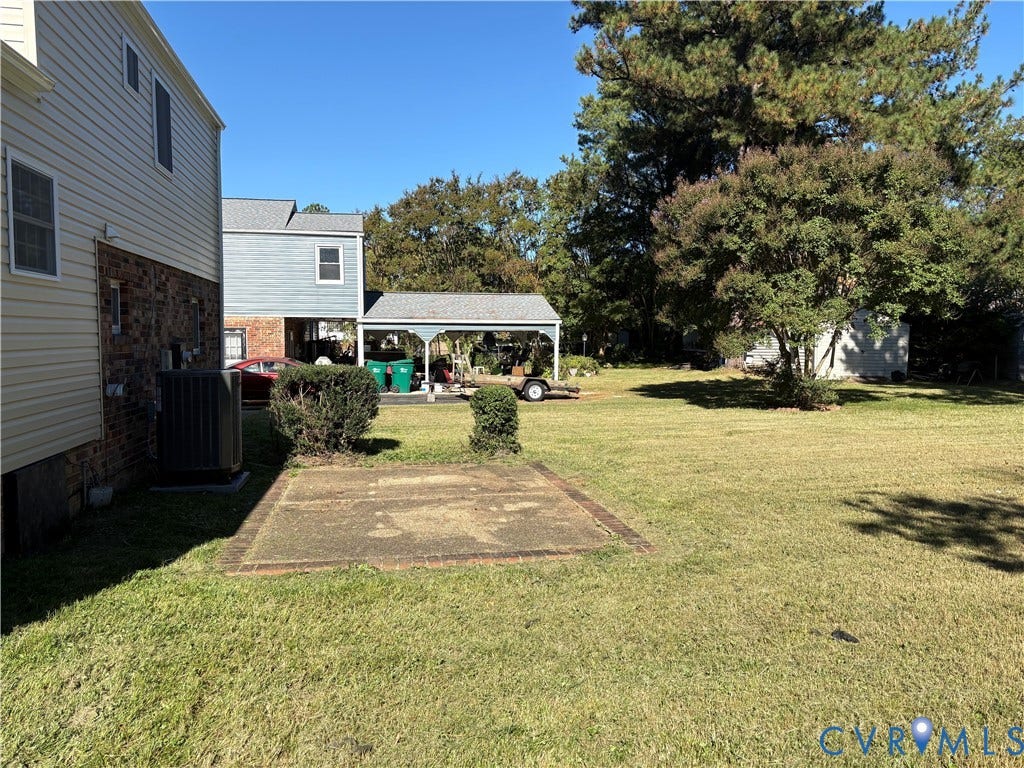 1708 Shewalt Drive, Fairfield, VA 23228 Expansive backyard featuring a concrete patio, covered parking structure, brick and siding exterior, and mature trees