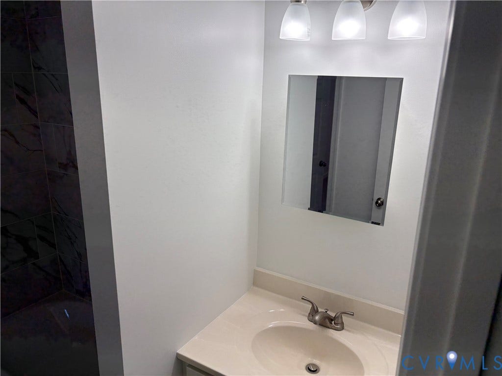 1708 Shewalt Drive, Fairfield, VA 23228 Bathroom 3rd level featuring a vanity with integrated sink, chrome double-handle faucet, wall-mounted mirror, three-light fixture, and tile shower surround