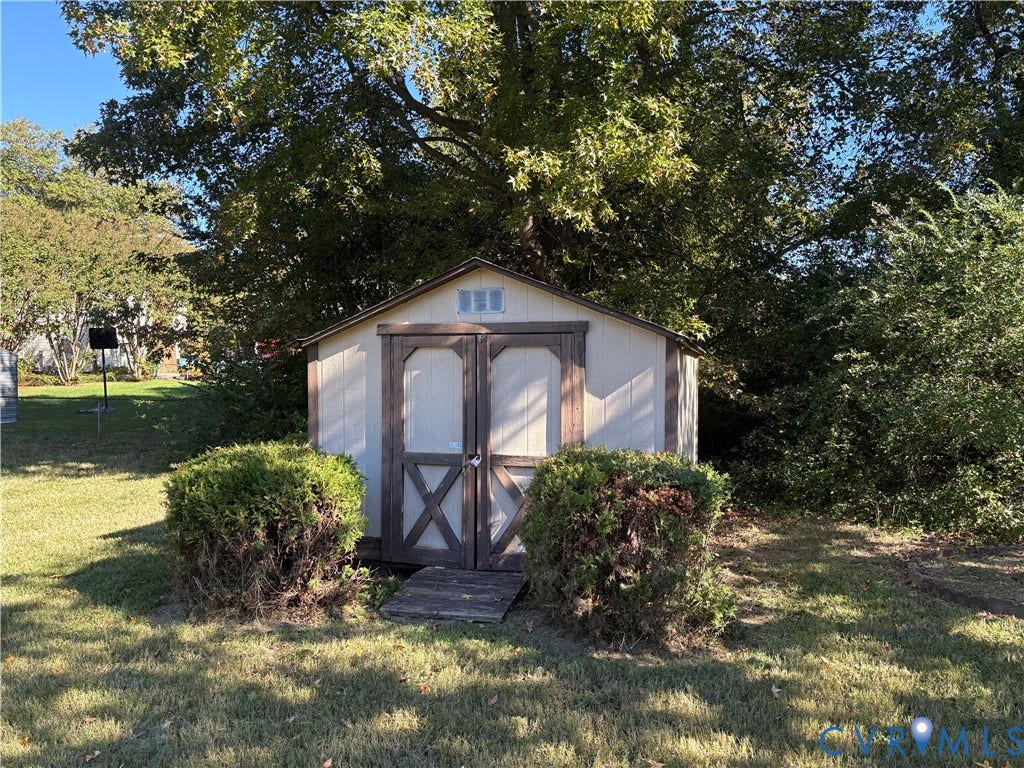 1708 Shewalt Drive, Fairfield, VA 23228 Exterior storage shed featuring double doors, a gable roof, and wood-finish trim, situated on a grassy lot with mature trees
